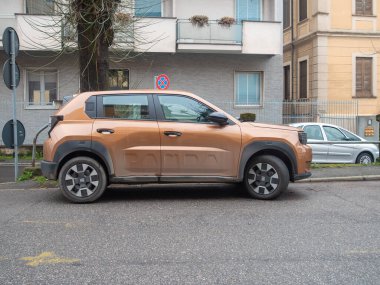 Cremona, İtalya 6 Şubat 2026 Yepyeni 2024 Fiat Grande Panda canlı turuncu renkli, elektrikli bir hibrit şehir SUV, kalabalık bir şehir asfalt yolunda park halinde bulundu.