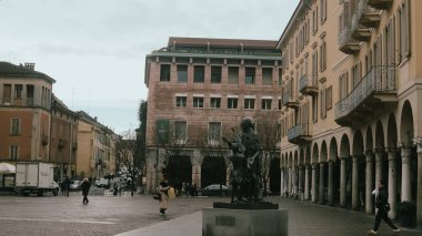 Cremona, İtalya 6 Şubat 2026 'da Piazza Roma, Cremona, Lombardy, İtalya' da belirgin bir şekilde dikilen Stradivari heykeli, tarihi binalar ve kemerlerle meydanı çerçeveliyor.