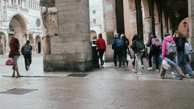 Cremona, İtalya 6 Şubat 2026 Islak kaldırım taşı caddesinde yürüyen insanlar tarihi Cremona, İtalya 'da antik taş binalar ve kemerli portikolarla sıralanmış.