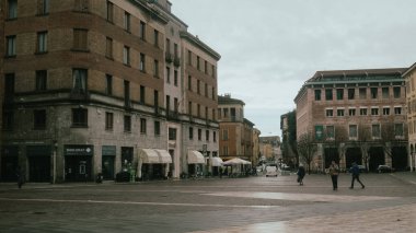 Cremona, İtalya 6 Şubat 2026 'da İtalya' nın Cremona kentindeki şehir meydanında, gri bir kış gökyüzü altında tarihi binalar ve yerel hayat yer alıyor ve kent mimarisini ön plana çıkarıyor.