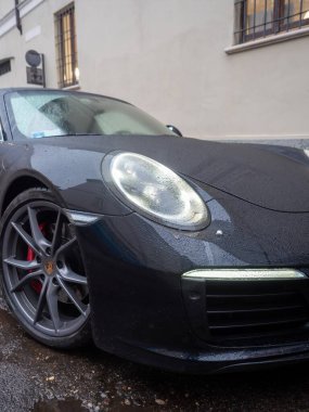 Cremona, İtalya - 6 Şubat 2026 Porsche 911 Carrera 4S (9991.2) hafif yağmurda önde, parlak ıslak dış ışık, asfalt üzerinde yansımalar, premium performans