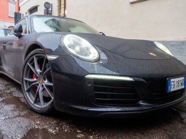 Cremona, İtalya - 6 Şubat 2026 Porsche 911 Carrera 4S (9991.2) ıslak şehir caddesinde, gösterişli modern tasarım, performans, lüks ve ıslak yol yansımaları