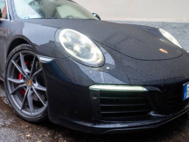 Cremona, İtalya - 6 Şubat 2026 Porsche 911 Carrera 4S (9991.2) ıslak şehir caddesinde, gösterişli modern tasarım, performans, lüks ve ıslak yol yansımaları