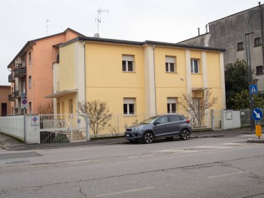 Cremona, İtalya - 7 Ocak 2026 Cremona, Lombardy, İtalya 'da bir cadde boyunca uzanan konut binaları, yol kenarında bulutlu bir gökyüzünün altında park edilmiş bir araba, tipik kent mimarisini yakalıyor.
