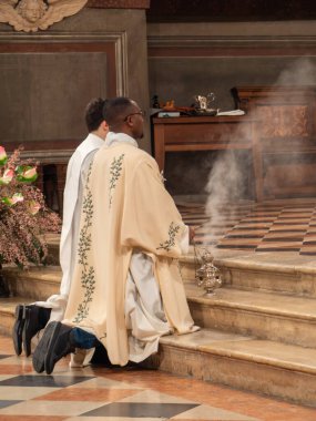 Cremona, İtalya 2 Şubat 2026 'da diz çöküp Katolik ayini sırasında sunağı yaktı. Sacristan, tarihi kilisenin içinde kutsal ibadete yardım ediyor.