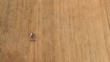 Traktör kuru bir alanda yeni sürülmüş toprağı düzleştiriyor, bahar tohumlama hazırlıkları sırasında toprağı işliyor, geleneksel tarım ve kırsal çalışmaları vurguluyor
