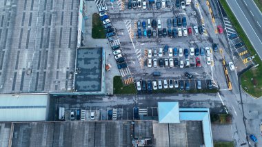 Vescovato, İtalya 7 Aralık 2025 Havadan bakıldığında birden fazla mağazası, kalabalık bir otoparkı ve otoyolda seyahat eden araçları olan canlı bir perakende parkı yakalıyor.