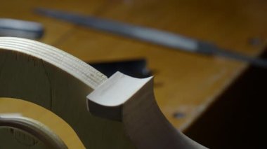İç küf üzerinde keman kaburgası şekillendirme Luthier, bir blok yakınında kaburga eğrisi pürüzsüz küçük bir el dosyası ile enstrüman yapımı sırasında vücut hatları ve yapısı rafine etmek için, el kameralı çekim yakın.