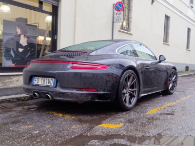 Cremona, İtalya - 3 Şubat 2026 Porsche 911 Carrera 991, yüksek performanslı lüks bir spor coupe, ıslak bir şehir sokağında duruyor.
