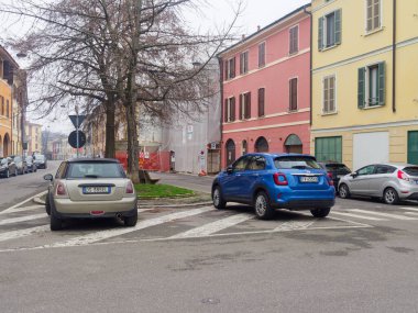 Cremona, İtalya - 3 Şubat 2026 İki kompakt araba, bir mavi Fiat 500X ve bir gümüş Mini Cooper, arka planda renkli binalar olan bir caddeye park edildi