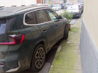 Cremona, İtalya - 3 Şubat 2026 modern koyu yeşil bir BMW X1 SUV dar bir şehir caddesinde sıkıca park edilmiş, arka tasarımı ve alaşım tekerlekleri sergilenmektedir.
