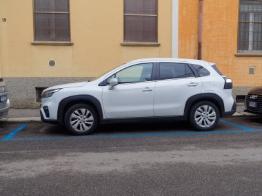 Cremona, İtalya - 3 Şubat 2026 modern beyaz Suzuki S-Cross marka bir SUV asfalt yüzeyinde mavi çizgilerle işaretlenmiş bir yere park edilmiştir.
