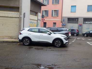 Cremona, İtalya - 3 Şubat 2026 modern beyaz bir Kia Sportage SUV diğer araçlar ve ticari binalarla çevrili kentsel bir çevrede ıslak bir asfalt yolda park edilmiştir.