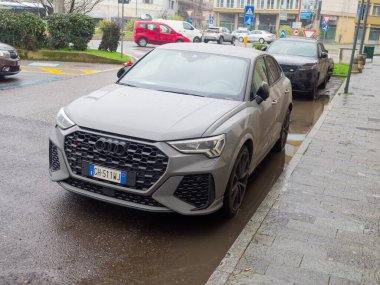 Cremona, İtalya - 3 Şubat 2026 Audi RS Q3 Sportback, yüksek performanslı gri bir SUV, İtalyan plakalı ıslak bir şehir caddesinde oturuyor, modern otomotiv tasarımı ve şehir planlarını yansıtıyor.