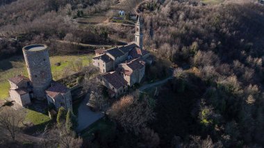 Monteventano Kalesi 'nin antik kulesi ve geleneksel binalardan yükselen çan kulesi Val Luretta manzarasının içindeki tarihi mimariyi vurguluyor.