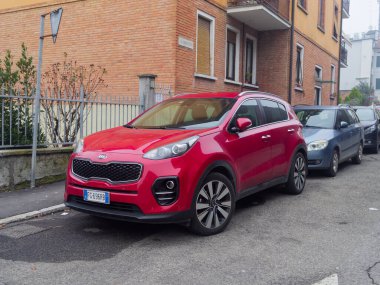 Cremona, İtalya - 26 Şubat 2026 Canlı kırmızı bir Kia Sportage SUV, modern tasarım ve alaşımlı tekerleklerini sergileyerek bir iskan caddesinde kaldırım kenarına park edilmiştir.