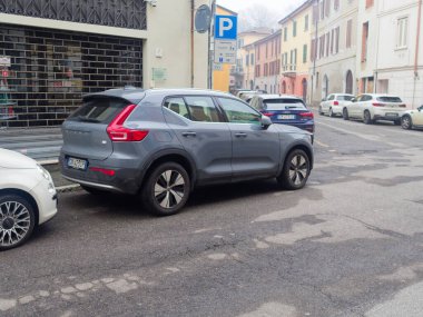 Cremona, İtalya - 26 Şubat 2026 Modern gri bir Volvo XC40 SUV, geleneksel Avrupa binaları ve diğer arabalarla dolu dar bir caddeye park edilmiştir.