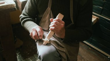 Bir zanaatkarın elleri, tarihi bir İtalyan Luthier stüdyosundaki oyma bir aletle ahşap bir keman tomarını dikkatlice şekillendirir.