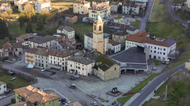 Büyüleyici Morfasso köyünü, merkez meydanını, tarihi kilisesini ve önde gelen saat kulesini gösteren bir hava perspektifi yakalıyor.