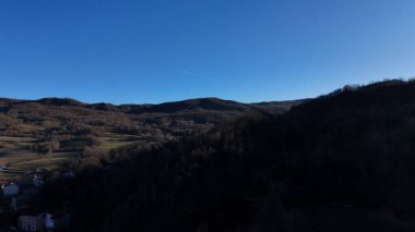 Morfasso 'nun pitoresk bir manzarası. Berrak mavi bir gökyüzünün altında yemyeşil, ağaçlarla kaplı tepelerle çevrili büyüleyici bir İtalyan köyü.