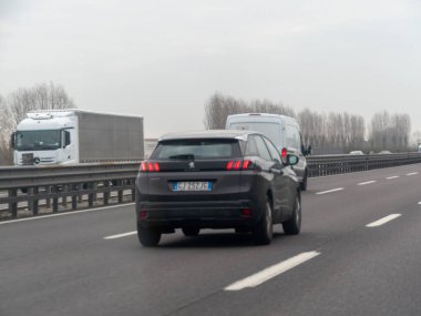 Venedik, A4 otoyolu, İtalya - 25 Şubat 2026 Koyu renkli bir Peugeot SUV İtalya 'da Autostrada A4' ün sağ şeridinde gri bir günde arka planda beyaz bir kamyon ve minibüsle ilerliyor.