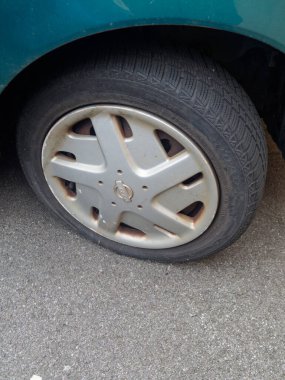 Cremona, İtalya - 17 Şubat 2026 Nissan aracının patlak lastiği, eskimiş lastik ve aşınmış alaşımlı tekerleği dokulu asfalt yüzeye karşı gösteriyor.