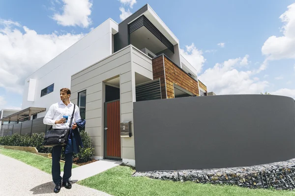 Junger Mann steht vor seinem modernen Haus — Stockfoto