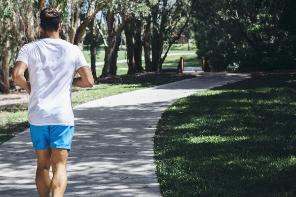 Young man running through park Stock Picture