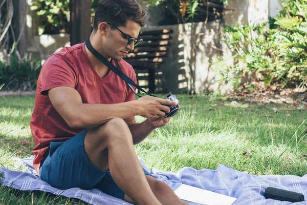 Hombre joven usando la cámara vintage en el parque Fotos De Stock