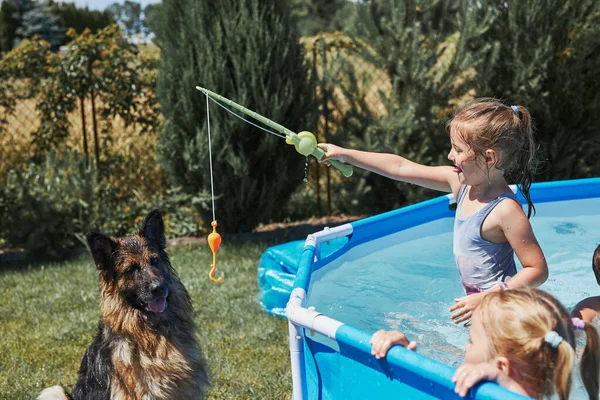 Çocuklar Evlerinin Bahçesinde Havuzda Duran Bir Olta Oyuncağıyla Köpekle Oynuyorlar — Stok fotoğraf