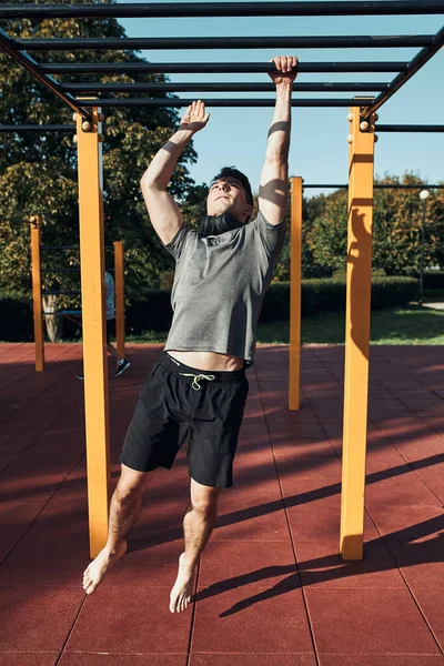 年轻的健美运动员在现代健美操街上的一个健身公园里 在猴栏上锻炼 穿着运动服的男人 — 图库照片