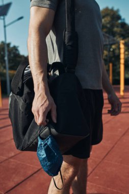 Sokak antrenman parkında elinde maske olan genç bir adam virüs enfeksiyonunu önlemek ve koronavirüs zamanında hastalığın yayılmasını önlemek için