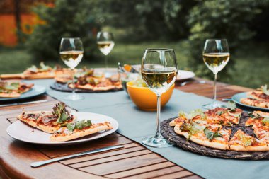 Ev bahçesinde akşam yemeği. Pizza, salata, meyve ve beyaz şarap arka bahçede bir meyve bahçesinde.