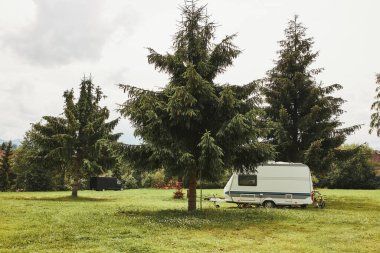 Karavan kamp alanındaki çam ağaçlarının arasından ayrıldı. Boşluğu üstte ve altta kopyala