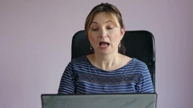 Uzaktan kumandayla video görüşmesi yapan bir kadın dizüstü bilgisayarda işini yapıyor. Ofiste latop kullanan bir kadın.