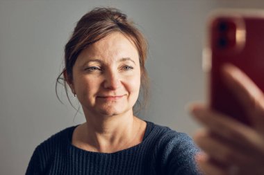 Bir kadın cep telefonuyla video görüşmesi yapıyor. Akrabalarla konuşmak. Akıllı telefon kullanarak selfie çekerken eğleniyorum. Mesafeyi koruyor. Aileye uzaktan bağlanma