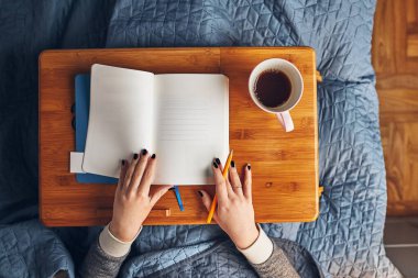 Öğrenciler evde öğreniyor. Not defterinden notlar alan, okuyan ve öğrenen genç bir kadın. Karantina sırasında yatakta oturan kız günlük yazıyor.