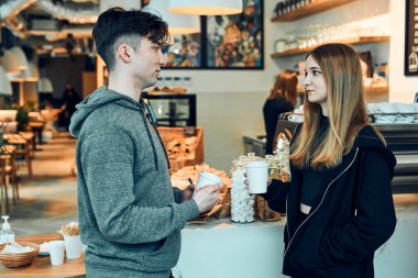 Dostlar sohbet ediyor, kahve fincanları tutuyor, bir kafede duruyor ve emirleri bekliyor. Kadın ve erkek kahve molası veriyorlar.