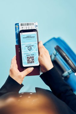 Dijital covid sertifikası. Kapsamlı aşı dijital geçiş kartı. Cep telefonu, pasaport ve uçak biletinde dijital kimlik kartı olan bir kadın. Sayısal covid test sonuçlarını covid-19 salgınında seyahat için tıbbi geçiş olarak gösteren bir gezgin