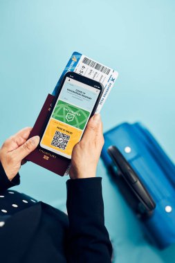 Dijital covid sertifikası. Kapsamlı aşı dijital geçiş kartı. Cep telefonu, pasaport ve uçak biletinde dijital kimlik kartı olan bir kadın. Sayısal covid test sonuçlarını covid-19 salgınında seyahat için tıbbi geçiş olarak gösteren bir gezgin