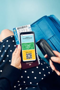 Dijital covid sertifikası. Kapsamlı aşı dijital geçiş kartı. Cep telefonu, pasaport ve uçak biletinde dijital kimlik kartı olan bir kadın. Sayısal covid test sonuçlarını covid-19 salgınında seyahat için tıbbi geçiş olarak gösteren bir gezgin