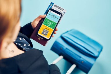 Dijital covid sertifikası. Kapsamlı aşı dijital geçiş kartı. Cep telefonu, pasaport ve uçak biletinde dijital kimlik kartı olan bir kadın. Sayısal covid test sonuçlarını covid-19 salgınında seyahat için tıbbi geçiş olarak gösteren bir gezgin