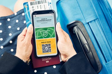 Dijital covid sertifikası. Kapsamlı aşı dijital geçiş kartı. Cep telefonu, pasaport ve uçak biletinde dijital kimlik kartı olan bir kadın. Sayısal covid test sonuçlarını covid-19 salgınında seyahat için tıbbi geçiş olarak gösteren bir gezgin