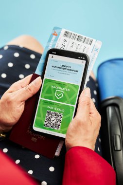 Dijital covid sertifikası. Kapsamlı aşı dijital geçiş kartı. Cep telefonu, pasaport ve uçak biletinde dijital kimlik kartı olan bir kadın. Sayısal covid test sonuçlarını covid-19 salgınında seyahat için tıbbi geçiş olarak gösteren bir gezgin