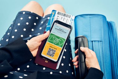 Dijital covid sertifikası. Kapsamlı aşı dijital geçiş kartı. Cep telefonu, pasaport ve uçak biletinde dijital kimlik kartı olan bir kadın. Sayısal covid test sonuçlarını covid-19 salgınında seyahat için tıbbi geçiş olarak gösteren bir gezgin
