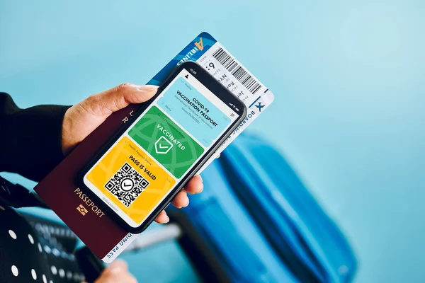 Digital covid certificate. Covid vaccination digital pass. Woman passenger holding digital medical pass on her mobile phone, passport and airplane ticket. Traveler showing digital covid test result as medical pass for travel during covid-19 pandemic