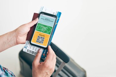 Dijital covid sertifikası. Covid negatif hızlı dijital test geçişi. Cep telefonu, pasaport ve uçak biletinde dijital kimlik kartı olan bir kadın. Sayısal covid test sonuçlarını covid-19 p sırasında seyahat için tıbbi geçiş olarak gösteren gezgin