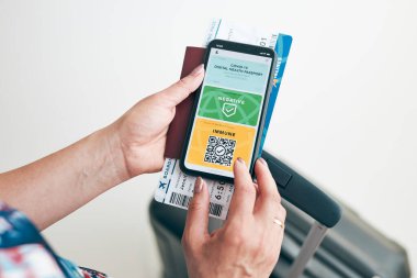 Dijital covid sertifikası. Covid negatif hızlı dijital test geçişi. Cep telefonu, pasaport ve uçak biletinde dijital kimlik kartı olan bir kadın. Sayısal covid test sonuçlarını covid-19 p sırasında seyahat için tıbbi geçiş olarak gösteren gezgin