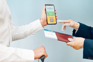 Dijital covid sertifikası. Kapsamlı aşı dijital geçiş kartı. Cep telefonu, pasaport ve uçak biletinde dijital kimlik kartı olan bir kadın. Sayısal covid test sonuçlarını covid-19 salgınında seyahat için tıbbi geçiş olarak gösteren bir gezgin