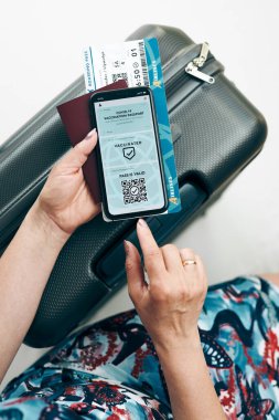 Dijital covid sertifikası. Covid negatif hızlı dijital test geçişi. Cep telefonu, pasaport ve uçak biletinde dijital kimlik kartı olan bir kadın. Sayısal covid test sonuçlarını covid-19 p sırasında seyahat için tıbbi geçiş olarak gösteren gezgin
